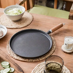 Fenn cast iron pan styled on a wood table with cabbage and cucumber